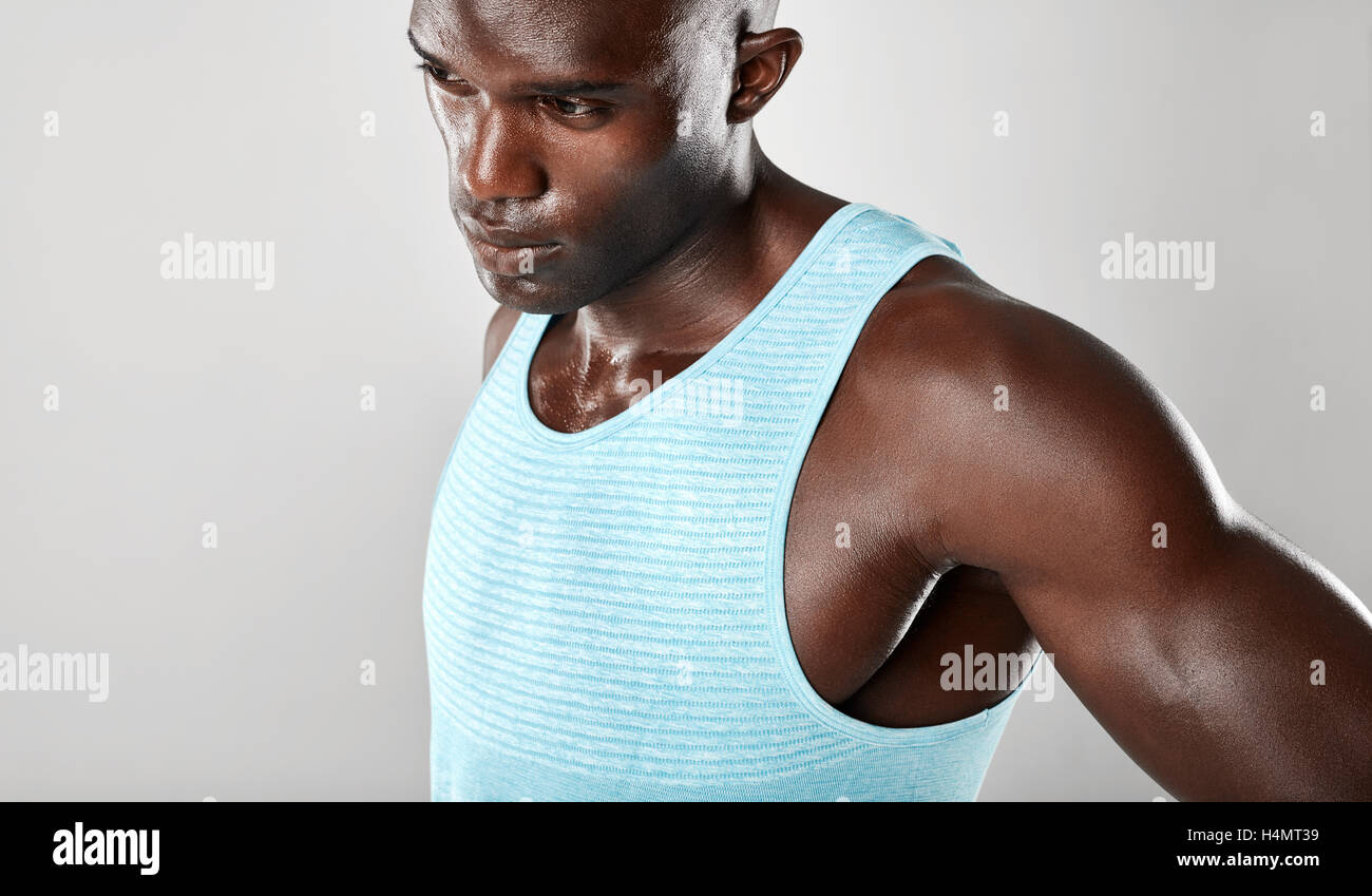 Schuss von Fit junger Mann muskulös steht vor grauem Hintergrund hautnah. Afro american Fitness Modell Wegsehen ein Stockfoto
