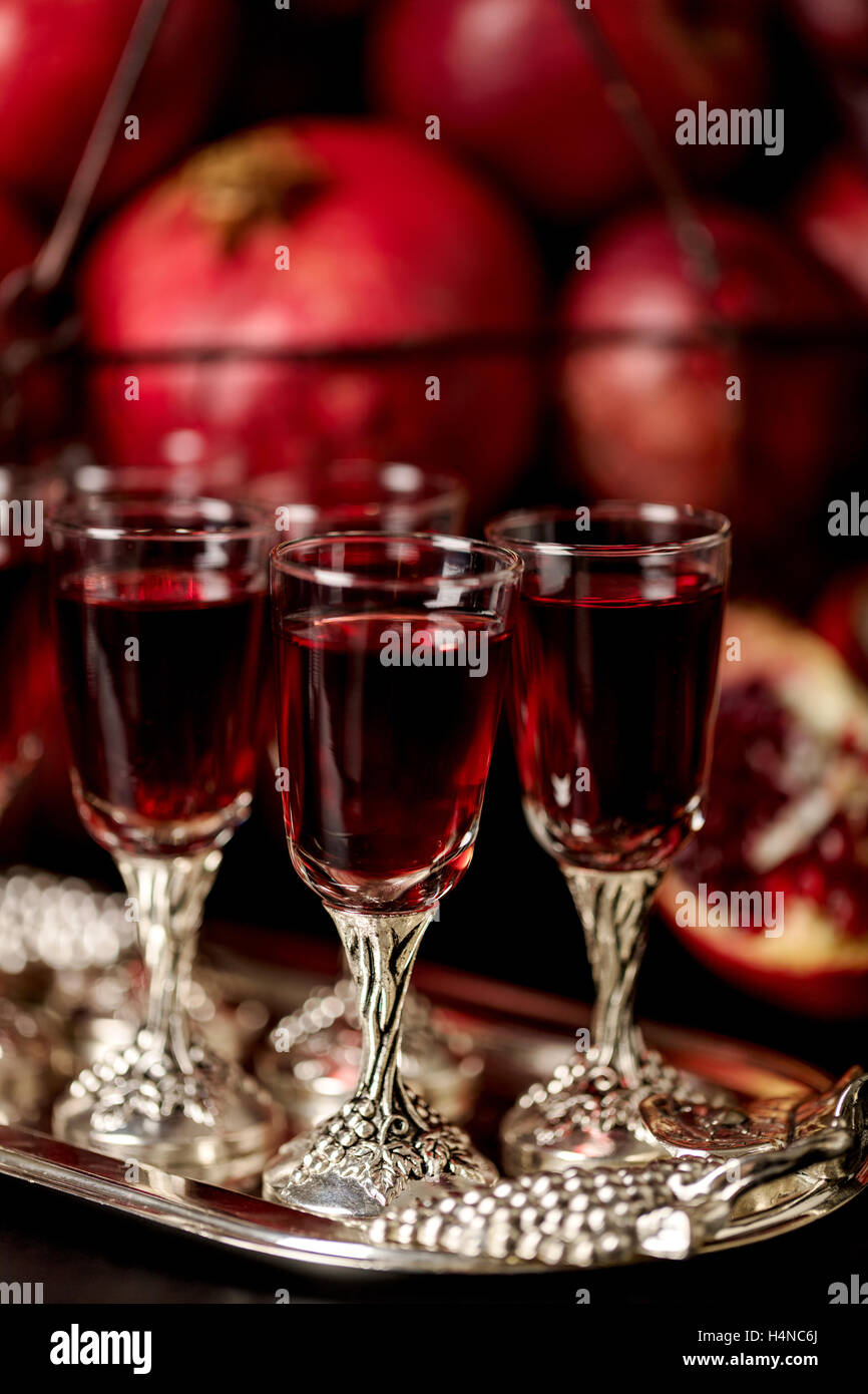 Still-Leben auf einem dunklen Hintergrund. Weingläser (Liquor), Früchte und Beeren (Äpfel, Granatäpfel und Trauben) in den Korb. Stockfoto