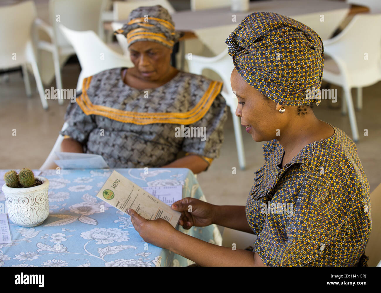 Porträt von zwei afrikanischen Frauen in traditionellen Seshweshwe Kleid Lesen der Speisekarte in einem Restaurant im freien Stockfoto