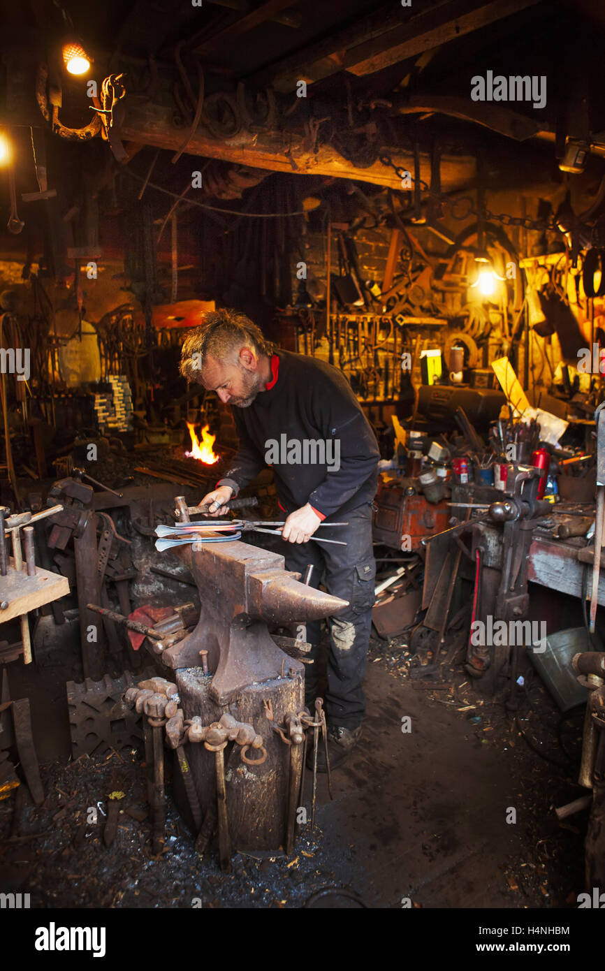 Schmied am Amboss in seiner Werkstatt. Stockfoto
