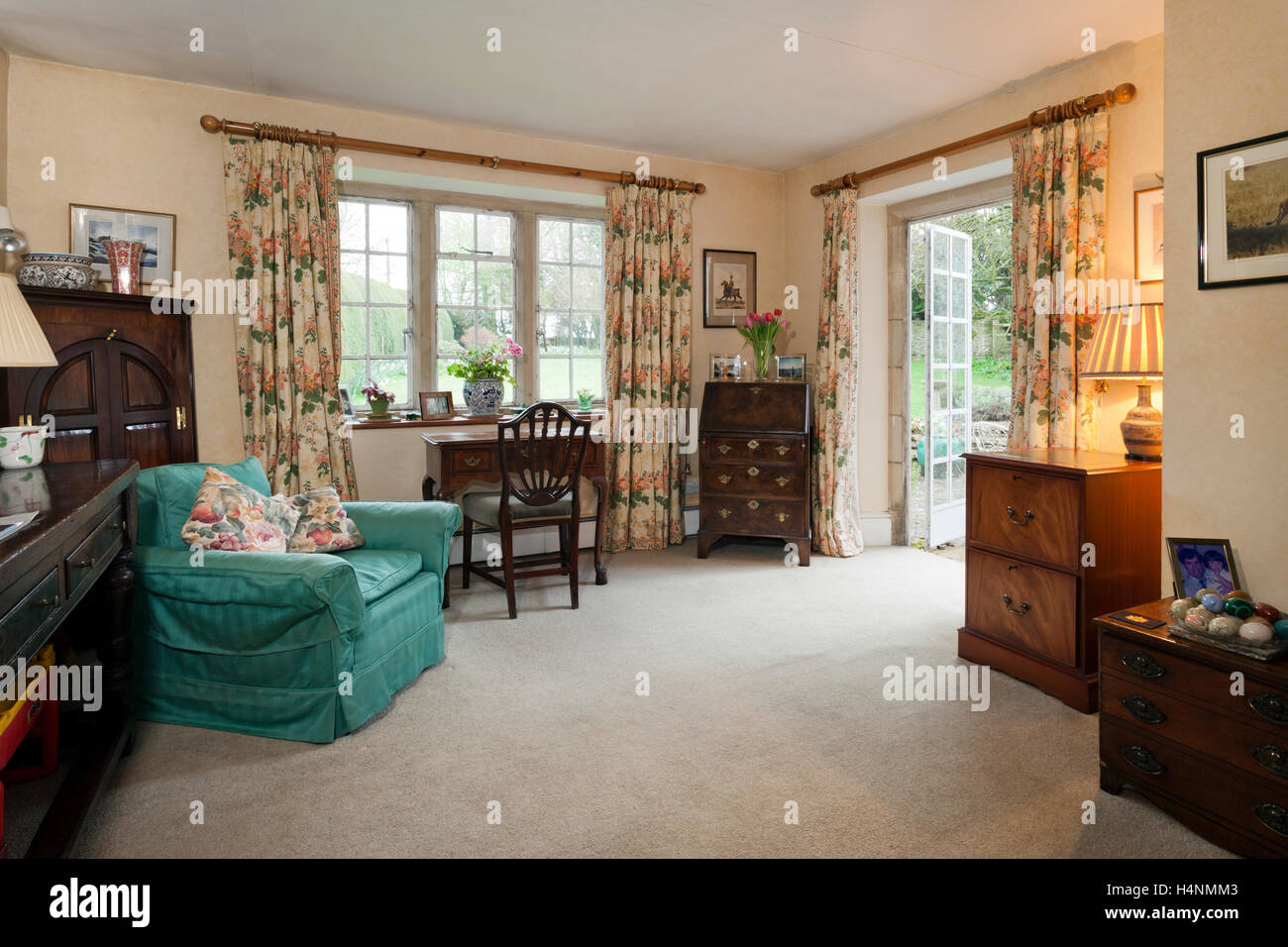 Traditionell eingerichtetes Wohnzimmer mit antiken Möbeln und Metall gerahmte Fenster und Balkontüre. Stockfoto