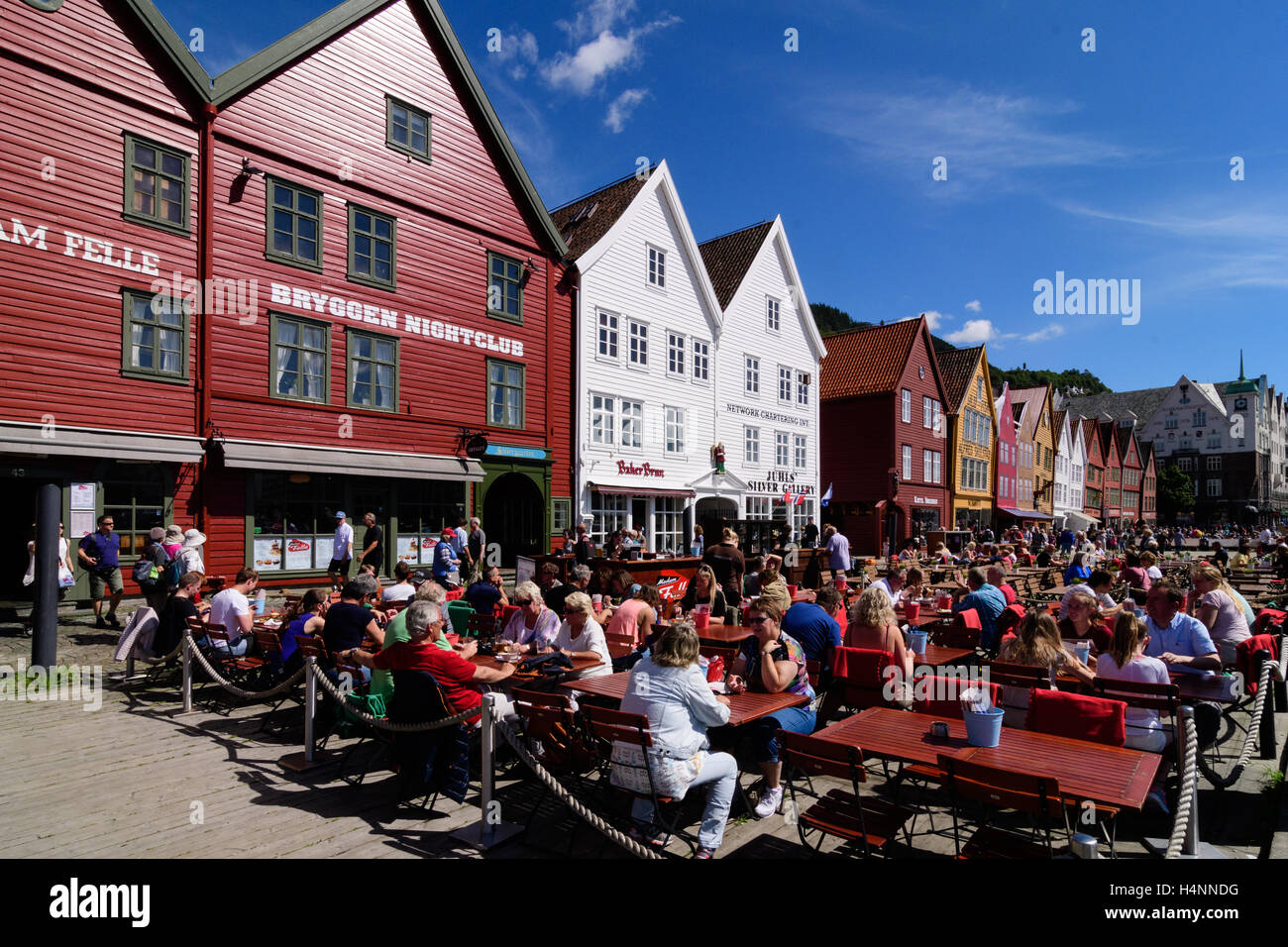 Touristen an einem warmen und sonnigen Sommertag ist Tag auf der Terrasse unter freiem Himmel haben Getränke und Mittagessen auf der UNESCO-Website mit historischen hölzernen Läden, Bryggen, Bergen, Norwegen Stockfoto