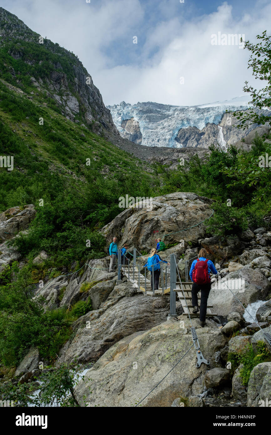 Tourist-Familie mit Kindern wandern über Felsen und Brücke zu den Buerbreen Gletscher Folgefonna Nationalpark, Norwegen Stockfoto