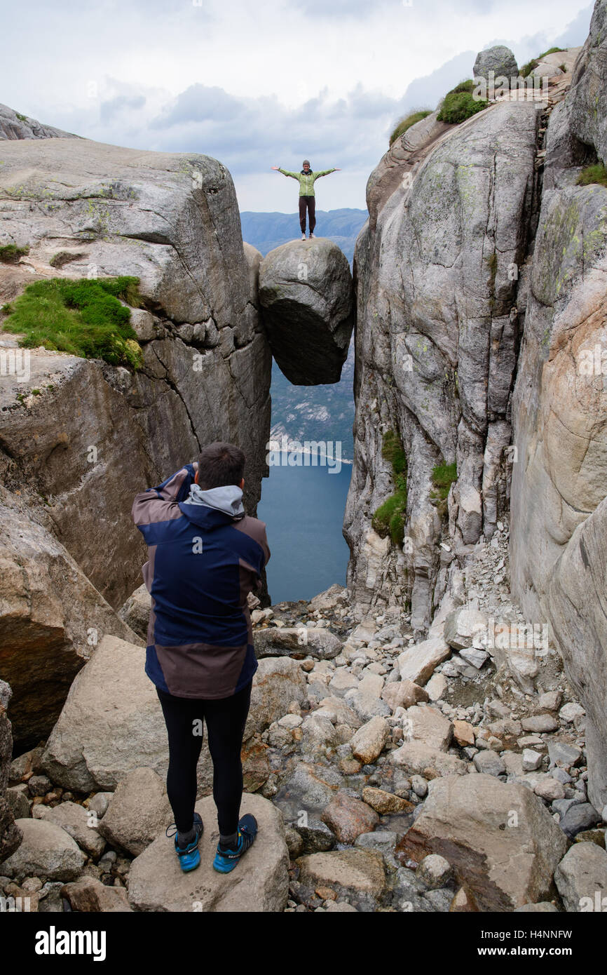 Touristen, die die Fotos von Freunden auf Kjeragbolten, einem Felsen hängen 1100 Meter über dem Fjord Lysefjord, Norwegen Stockfoto