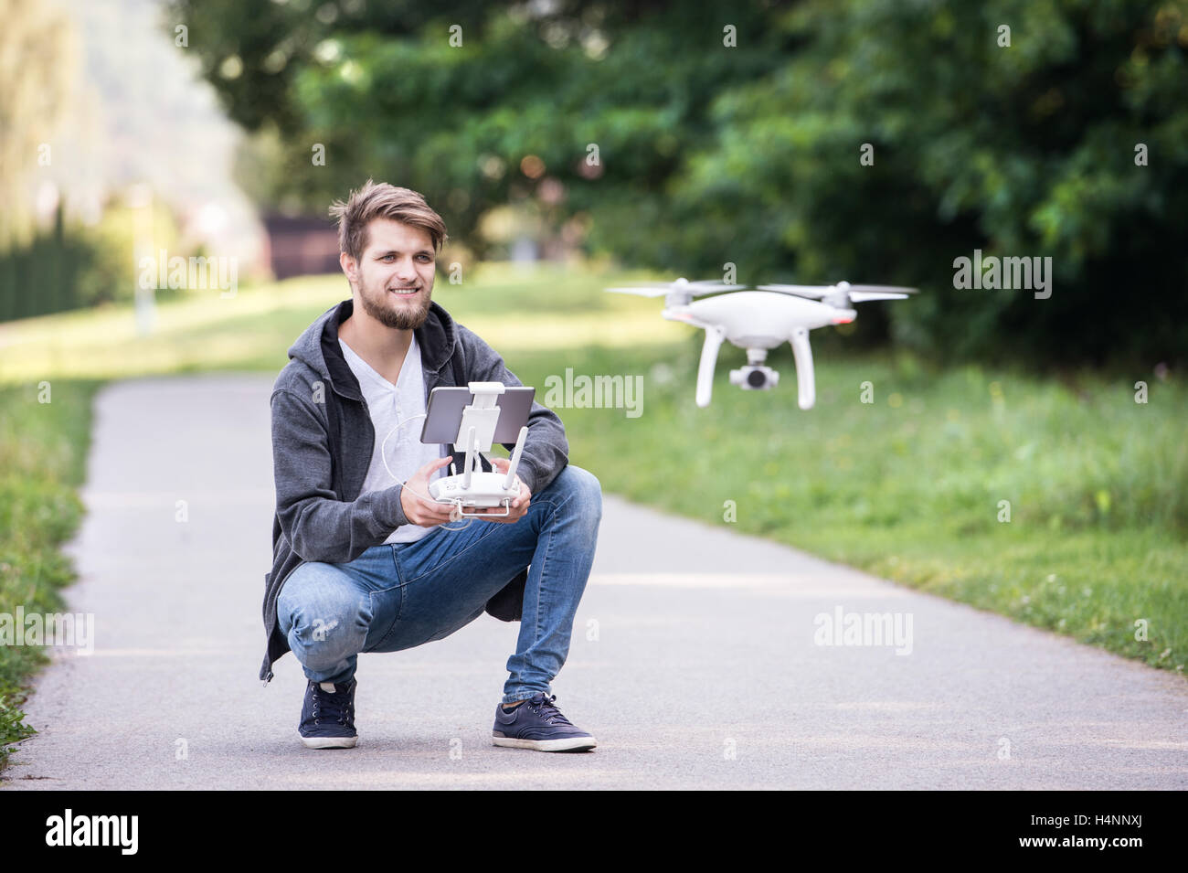 Junge Hipster Mann mit fliegenden Drohne. Sonnigen grünen Natur. Stockfoto