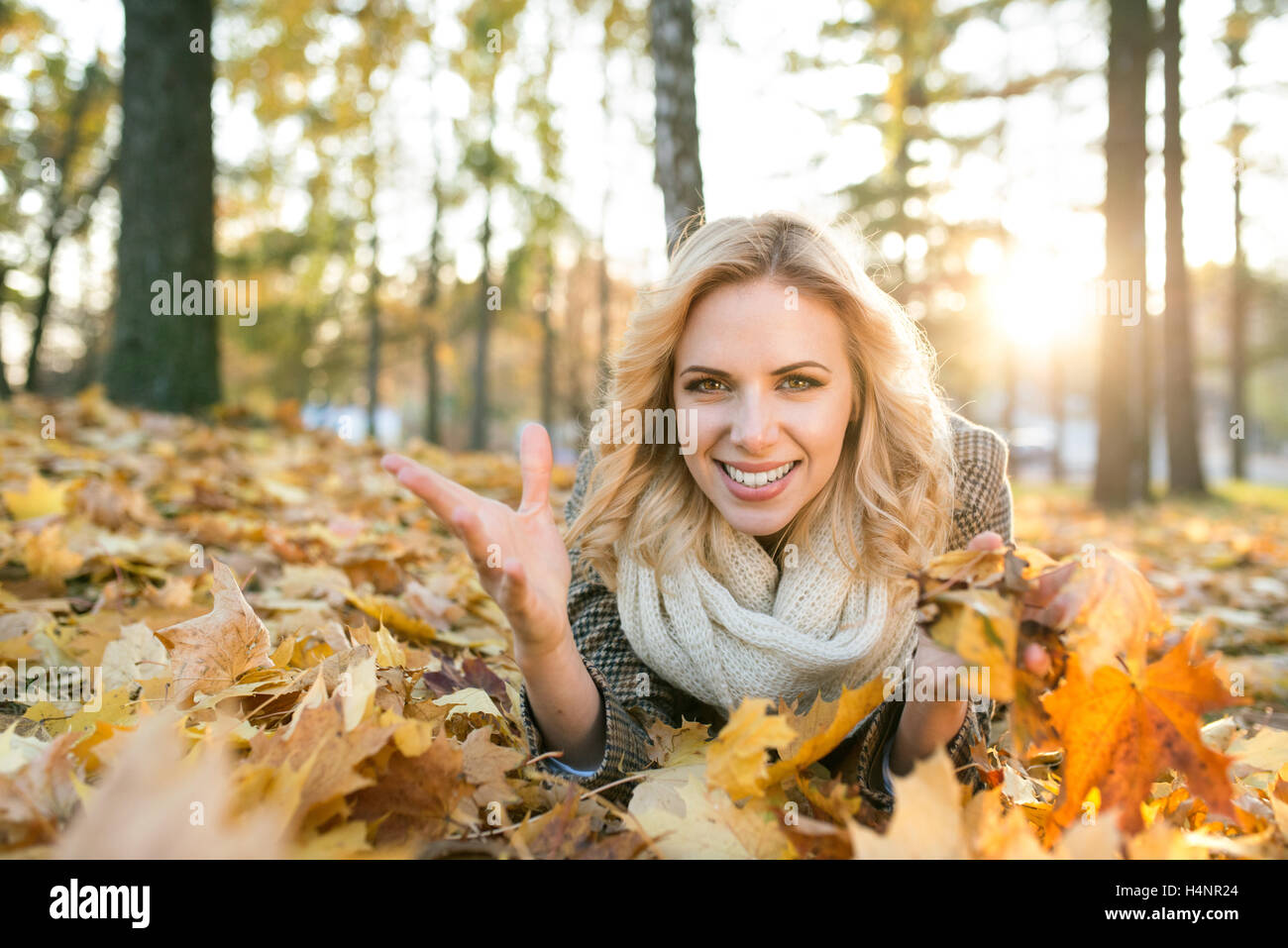 Schöne blonde Frau auf dem Boden im Herbst Park liegen Stockfoto