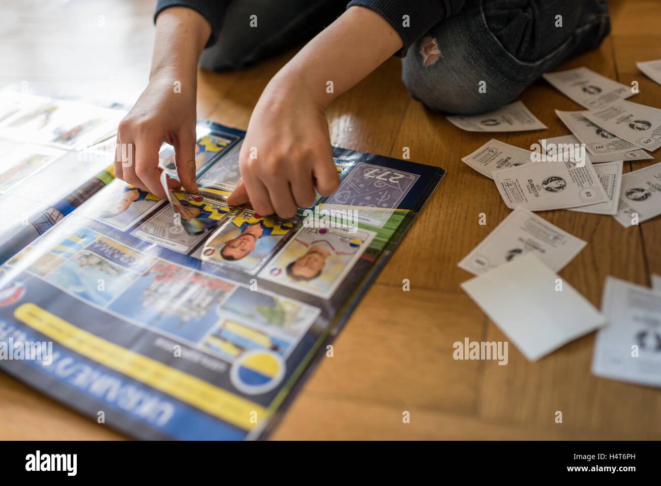 Ein 8 Jahre alter Junge ist in seinem Aufkleber Sammlung Sammelalbum UEFA Euro 2016 Panini Fußball-Sammelkarten einfügen. Stockfoto