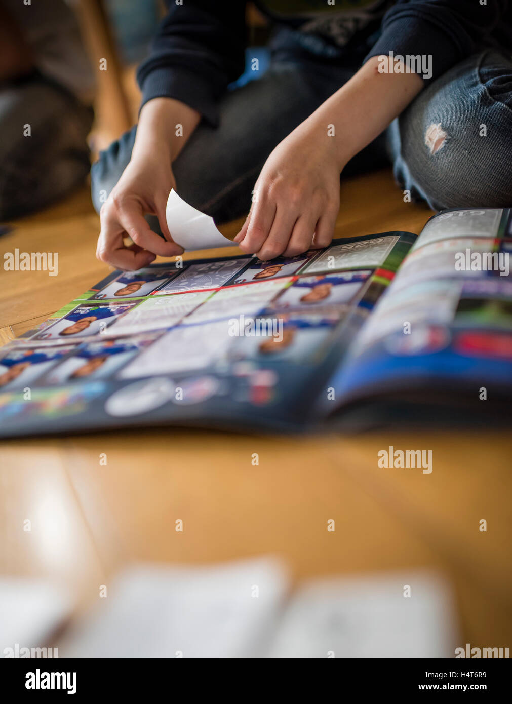 Ein 8 Jahre alter Junge ist Fußball-Sammelkarten in seinem Aufkleber Sammlung Sammelalbum einfügen. Stockfoto