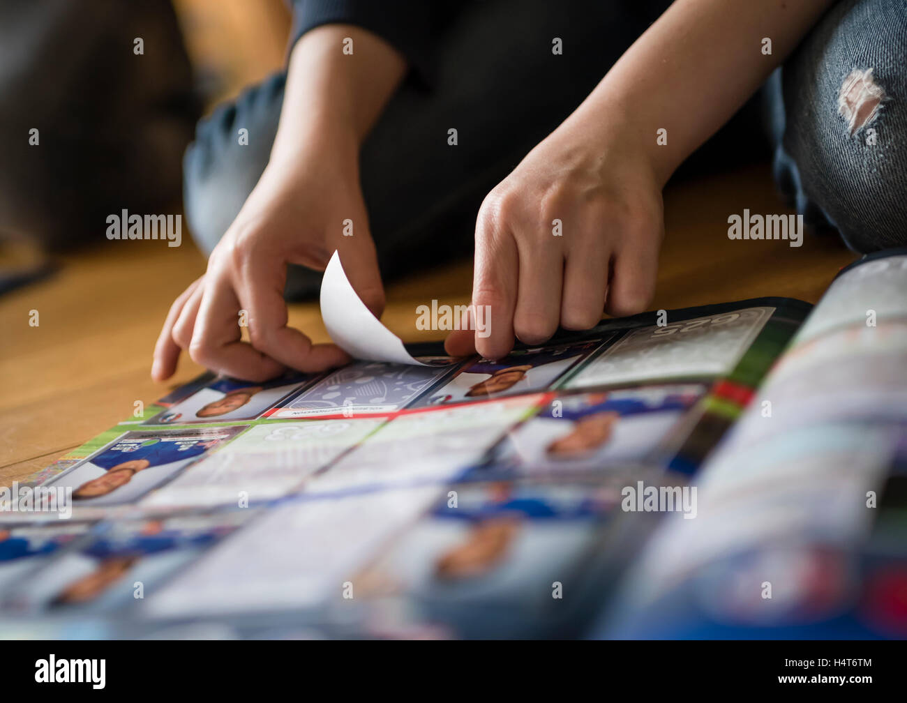Ein 8 Jahre alter Junge ist Fußball-Sammelkarten in seinem Aufkleber Sammlung Sammelalbum einfügen. Stockfoto