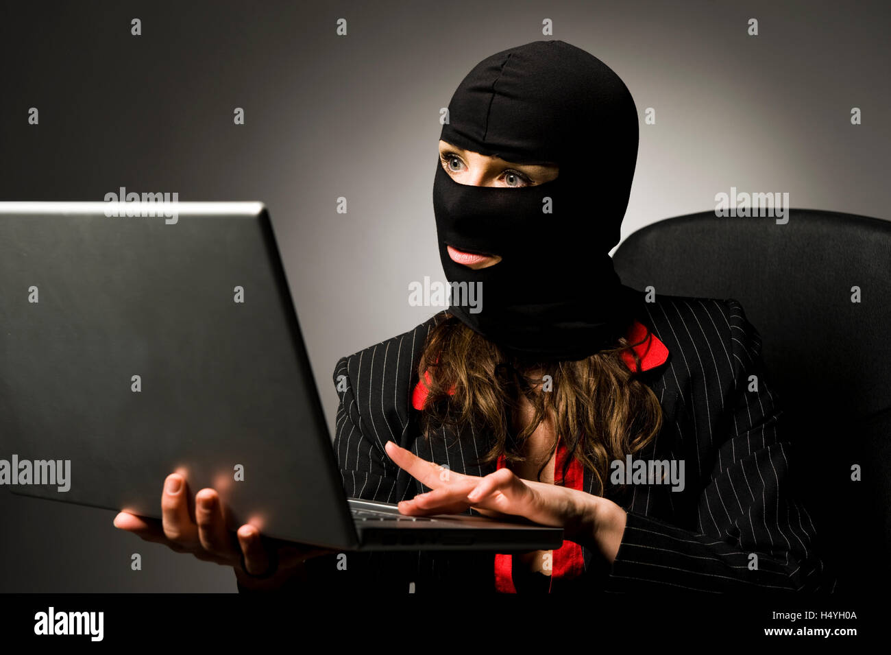 Maskierte Einbrecher mit Laptop, Wirtschaftsspionage, Datenpiraterie Stockfoto