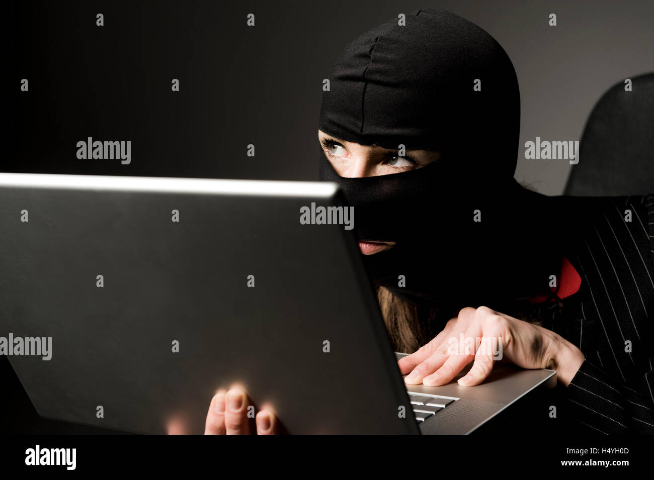 Maskierte Einbrecher mit Laptop, Wirtschaftsspionage, Datenpiraterie Stockfoto