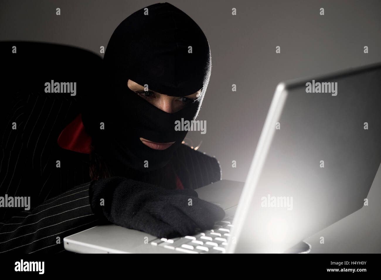Maskierte Einbrecher mit einem Laptop, Wirtschaftsspionage, Datenpiraterie Stockfoto