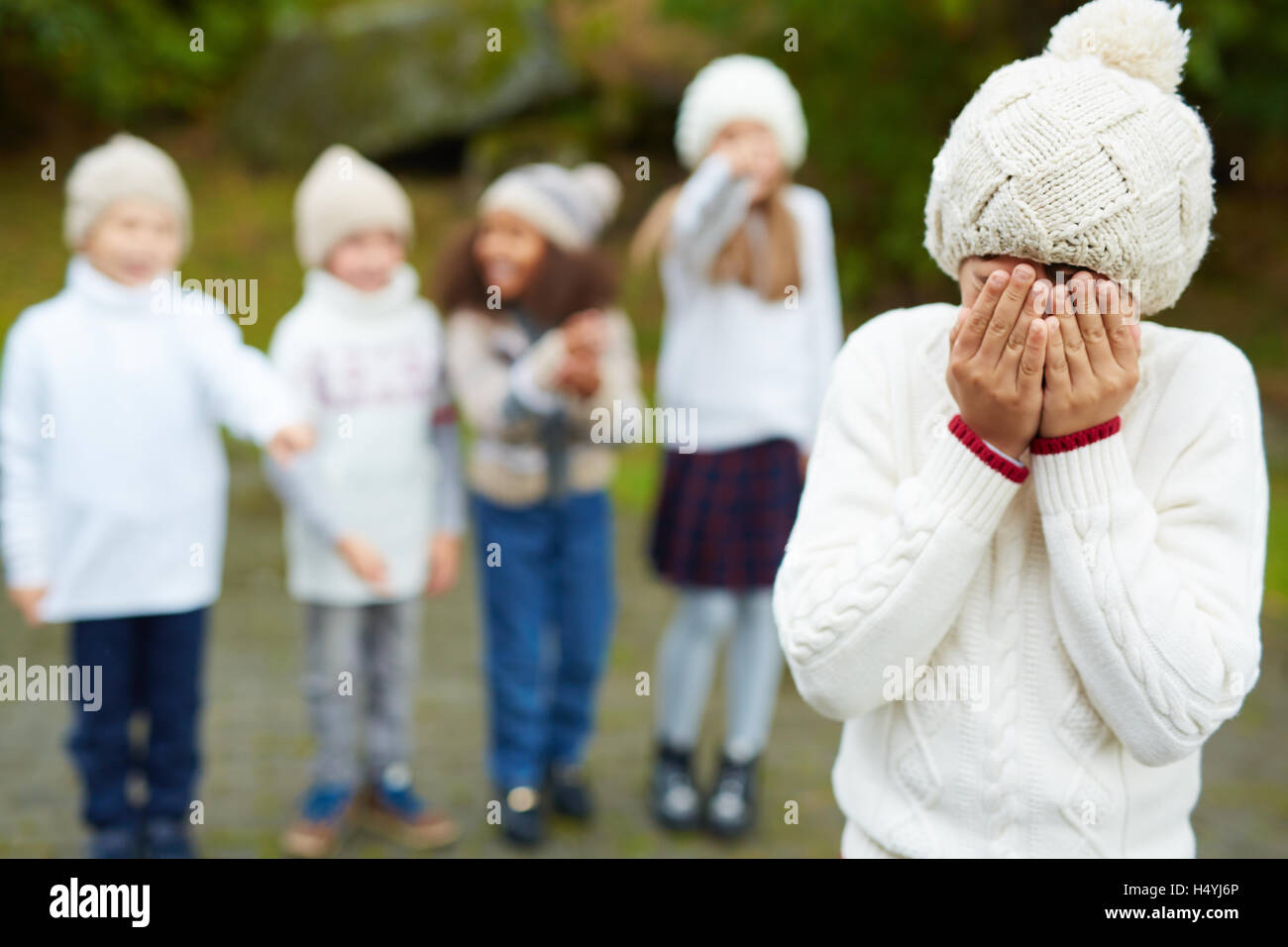 Junge mit Gruppe von Kindern Mobbing ihn weinen Stockfoto