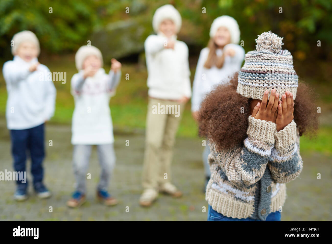 Afroamerikanische Mädchen mit dem Ausdruck ihrer tiefen verärgert während mehrere Kinder ihr Mobbing Stockfoto
