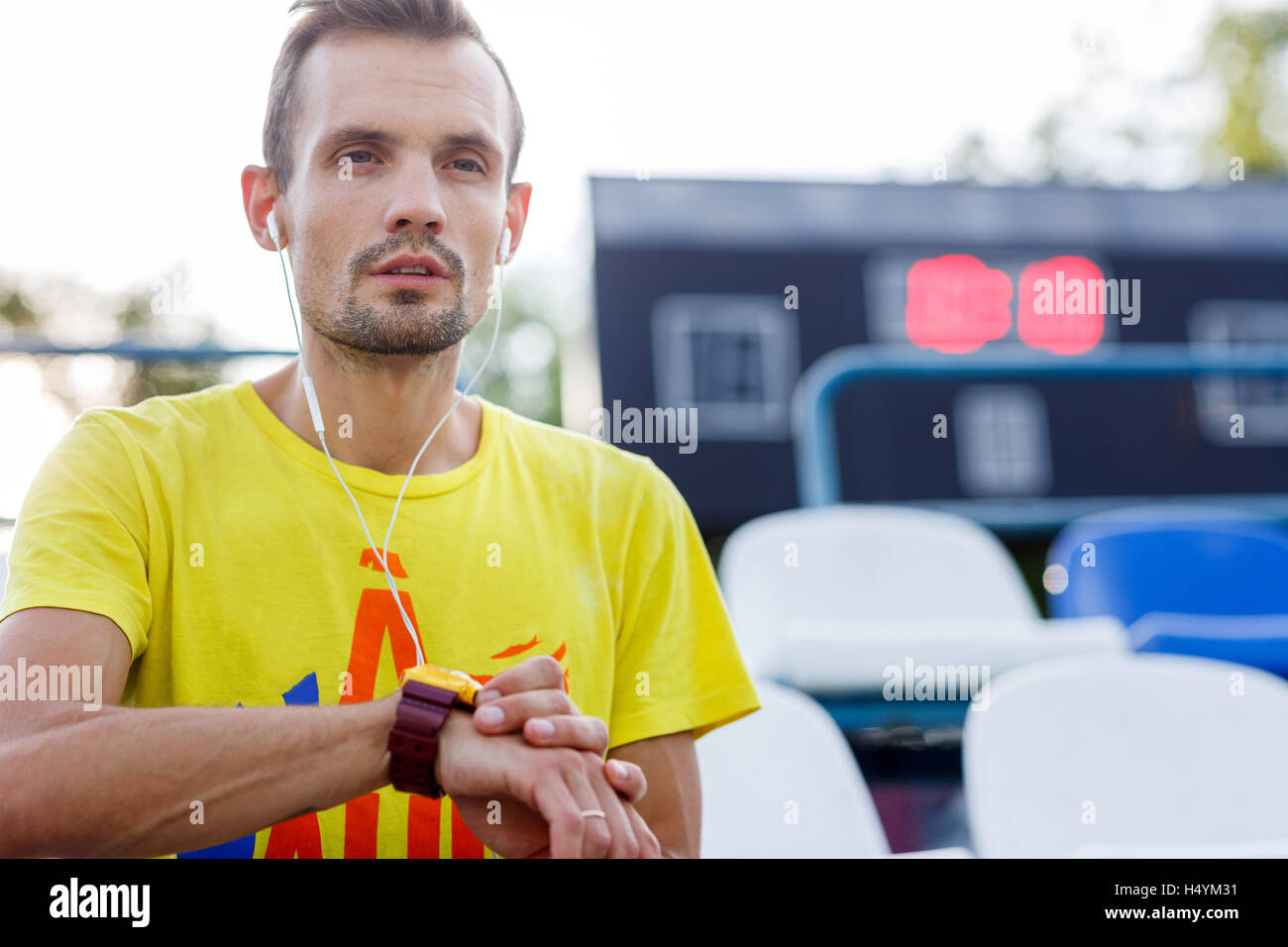 Sportlichen Mann im Kopfhörer und mit Uhr im Stadion Stockfoto