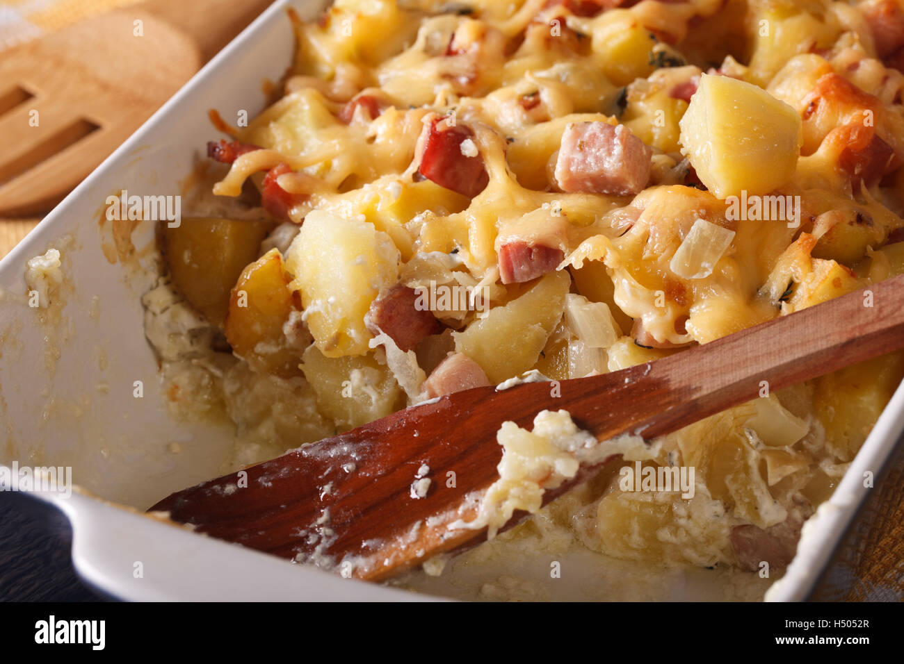 Französische Küche: Tartiflette Kartoffeln mit Speck und Käse hautnah in Auflaufform legen. Horizontale Stockfoto