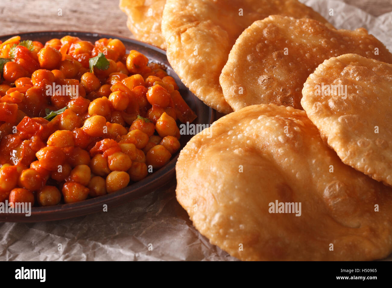 Indisches Brot Puri und Chana Masala Makro auf dem Tisch. Horizontale Stockfoto