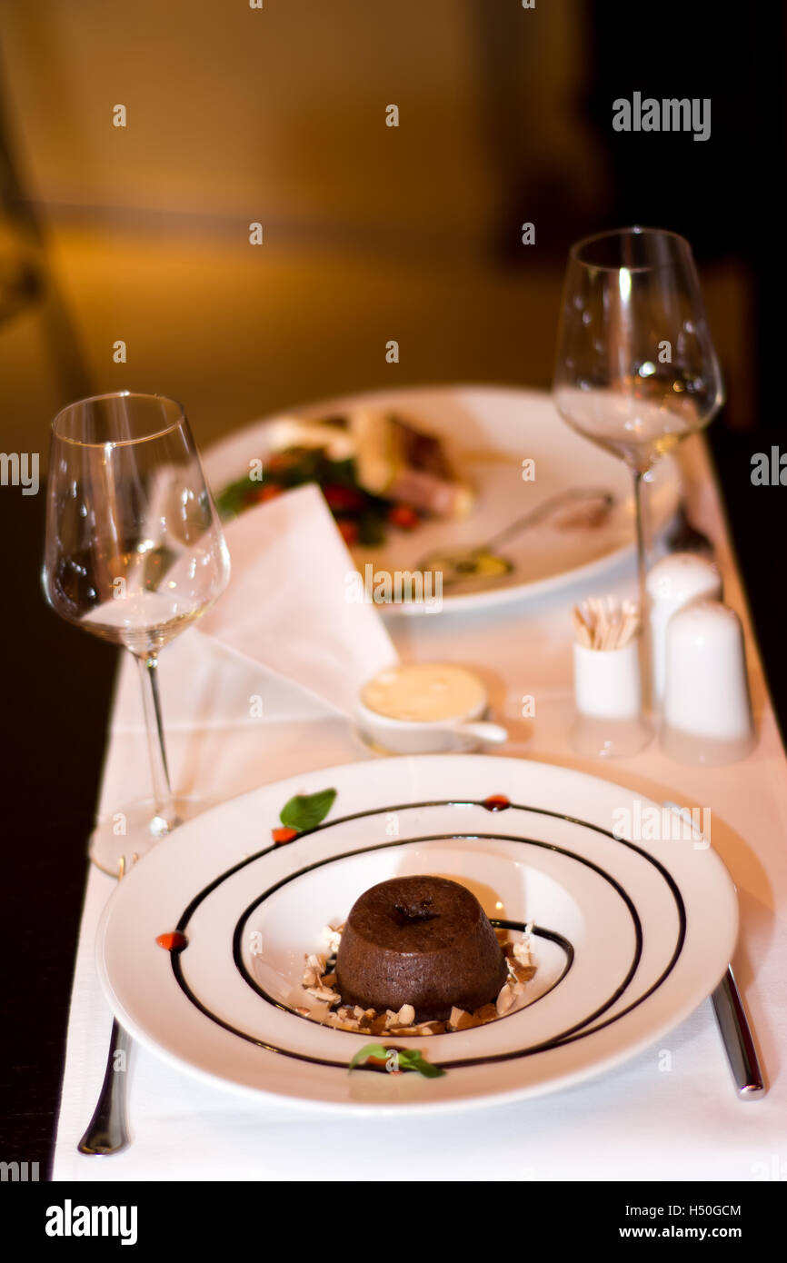 Es ist ein romantisches Abendessen zu zweit. Ein Soufflé ist wunderschön auf einem Tisch im stilvollen Restaurant mit Wein Gläser serviert. Stockfoto