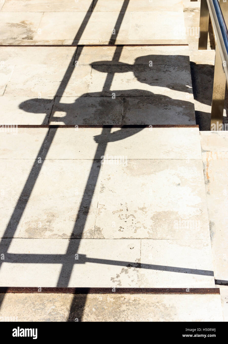 Geometrische abstrakte Komposition der Schatten von zwei Personen und einem Handlauf auf gepflasterten Schritte cast Stockfoto