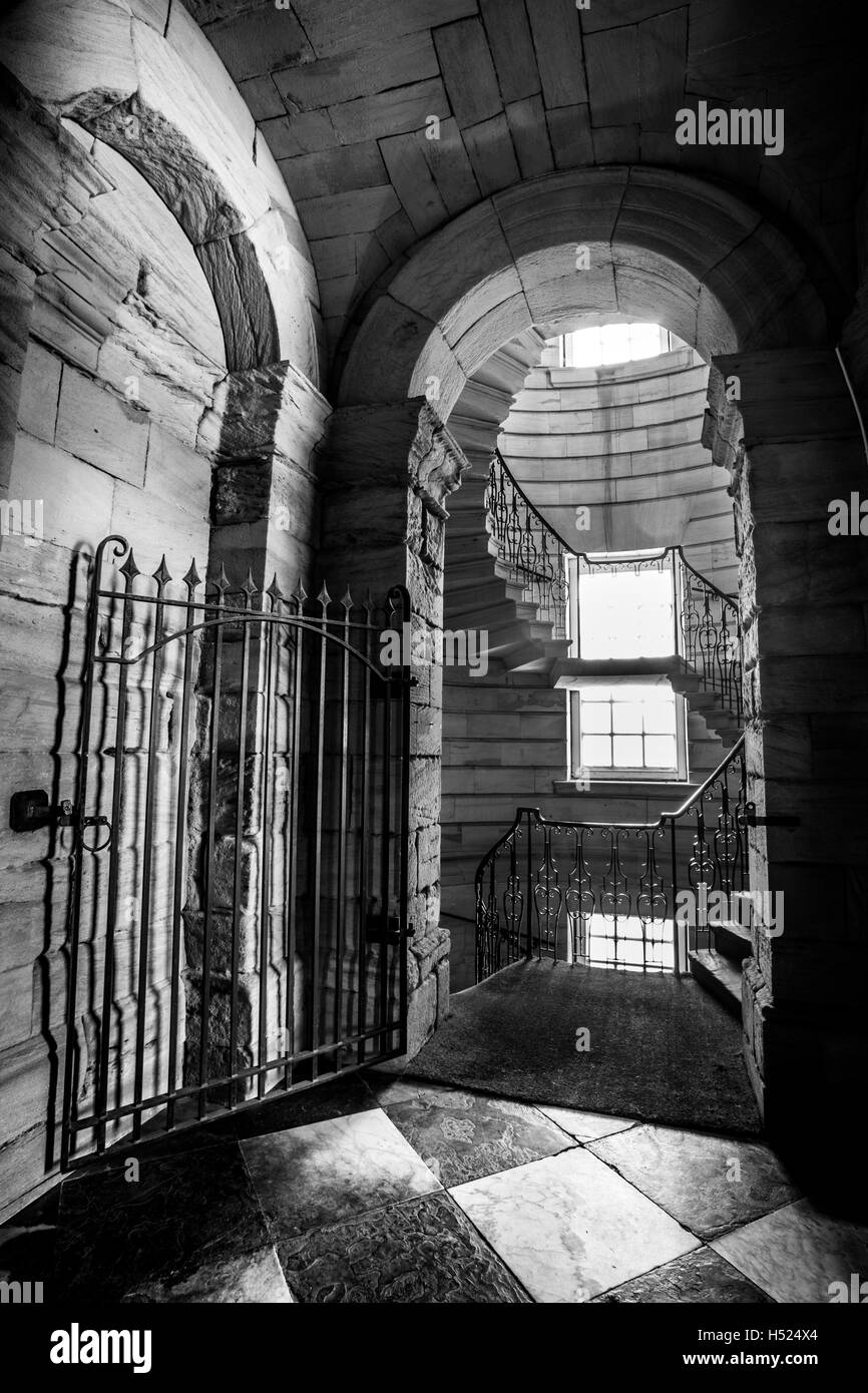 Gefliesten Flur und Eisernes Tor führt in eine Wendeltreppe in einem alten, historischen Gebäude, aus dem Schatten ins Licht Stockfoto