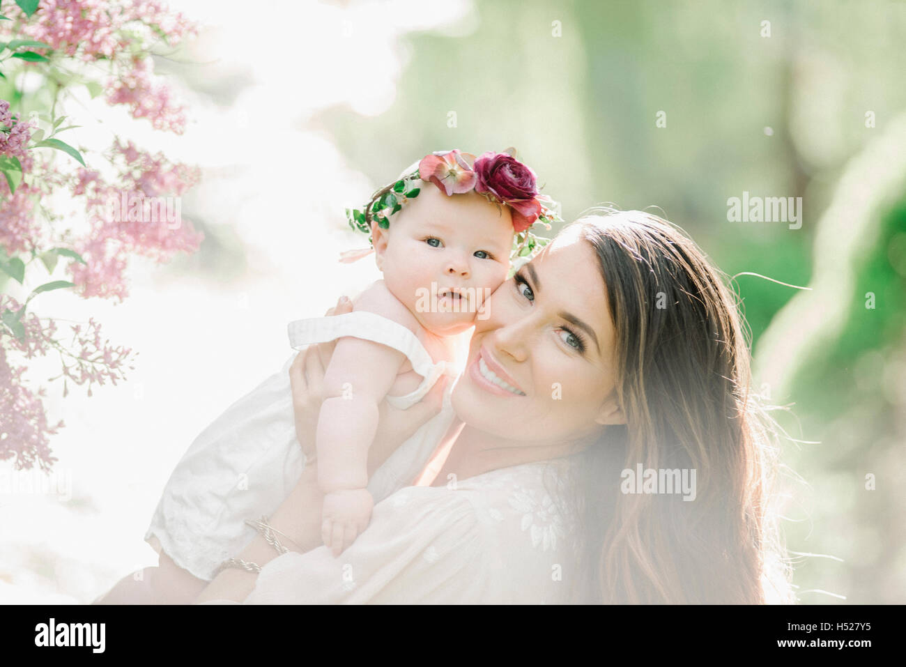 Porträt einer lächelnden Mutter und Babymädchen mit einem Blumen-Kranz auf dem Kopf. Stockfoto