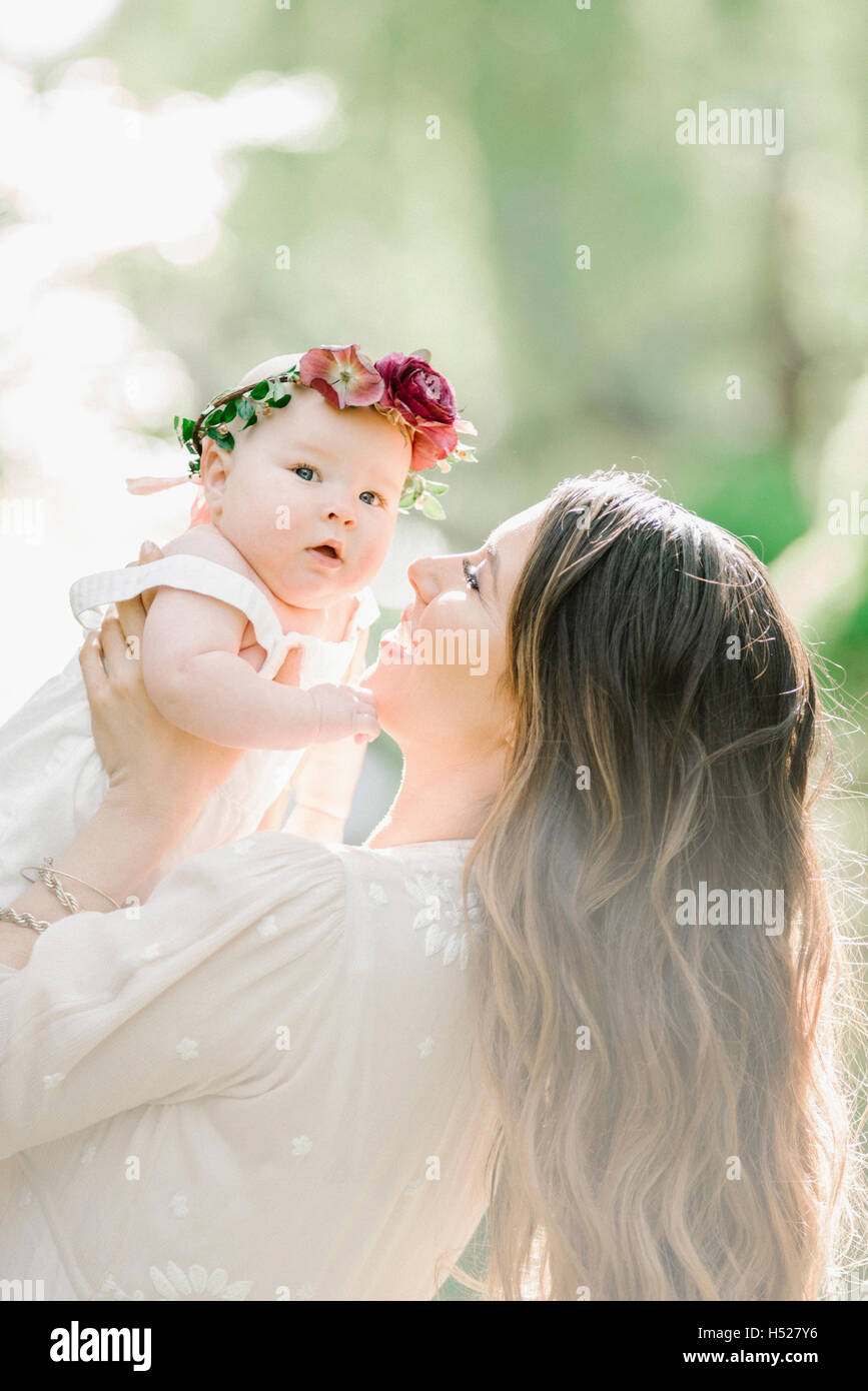 Porträt einer lächelnden Mutter und Babymädchen mit einem Blumen-Kranz auf dem Kopf. Stockfoto