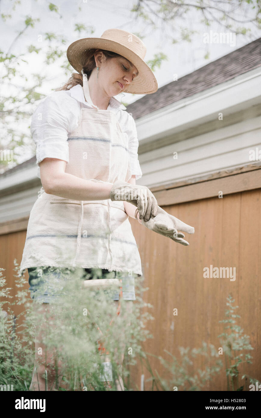 Frau mit Hut und Gartenarbeit Handschuhe, Schürze, im Freien. Stockfoto