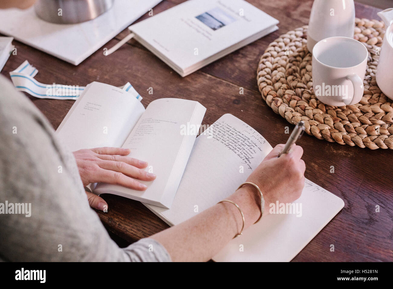 Frau sitzt an einem Tisch in ihrer Wohnung in ein Tagebuch, morgendlichen Routine zu schreiben. Stockfoto