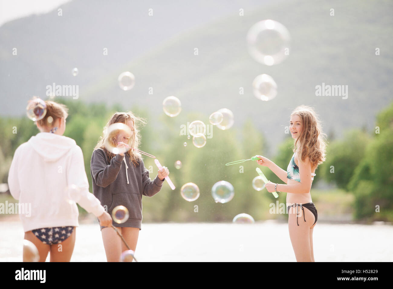 Mädchen im Teenageralter an einem See, umgeben von Seifenblasen. Stockfoto