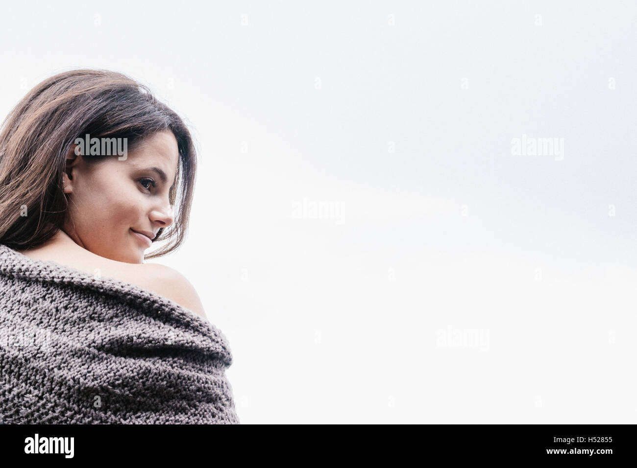 Frau mit langen braunen Haaren in eine Decke gehüllt über die Schulter schauen. Stockfoto