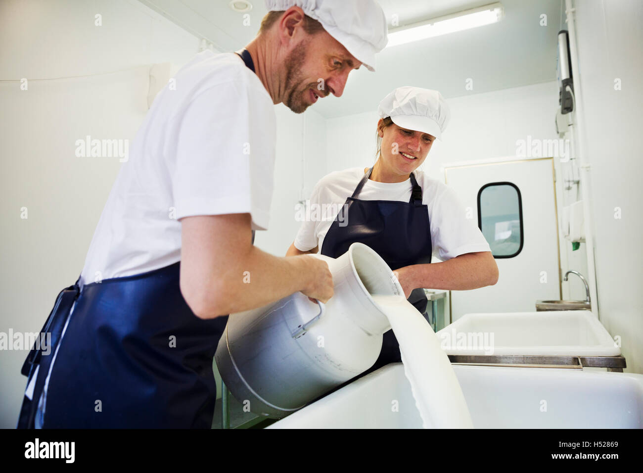 Mann und Frau in einer Molkerei, Gießen Ziegen Milch von einer Abwanderung zu Ziegenkäse. Stockfoto
