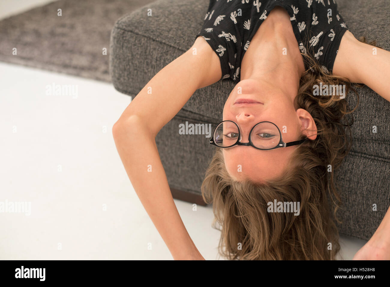 Mädchen mit Brille auf dem Kopf stehend auf einem Sofa liegend. Stockfoto