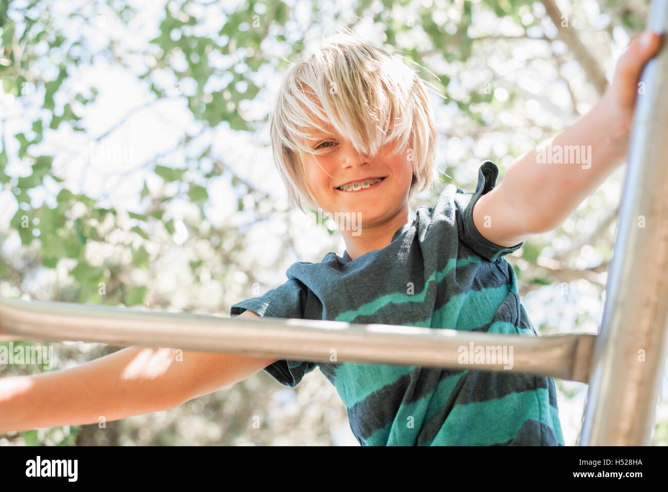 Blonder Junge auf einem Klettergerüst im Garten. Stockfoto