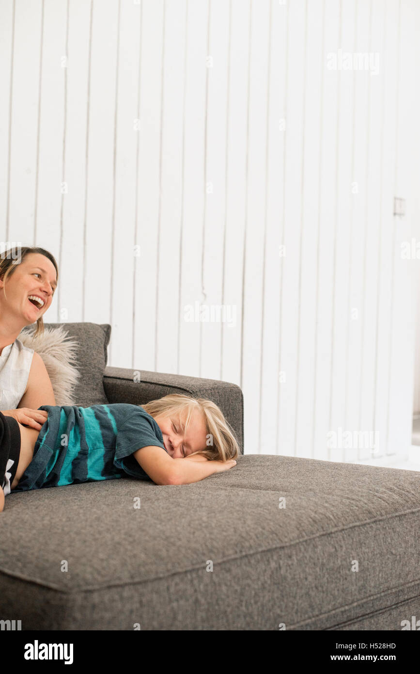 Lächelnde Mutter und Sohn auf einem Sofa liegend. Stockfoto