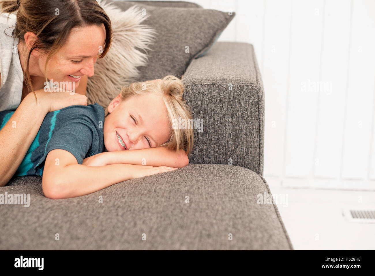 Lächelnde Mutter und Sohn auf einem Sofa liegend. Stockfoto