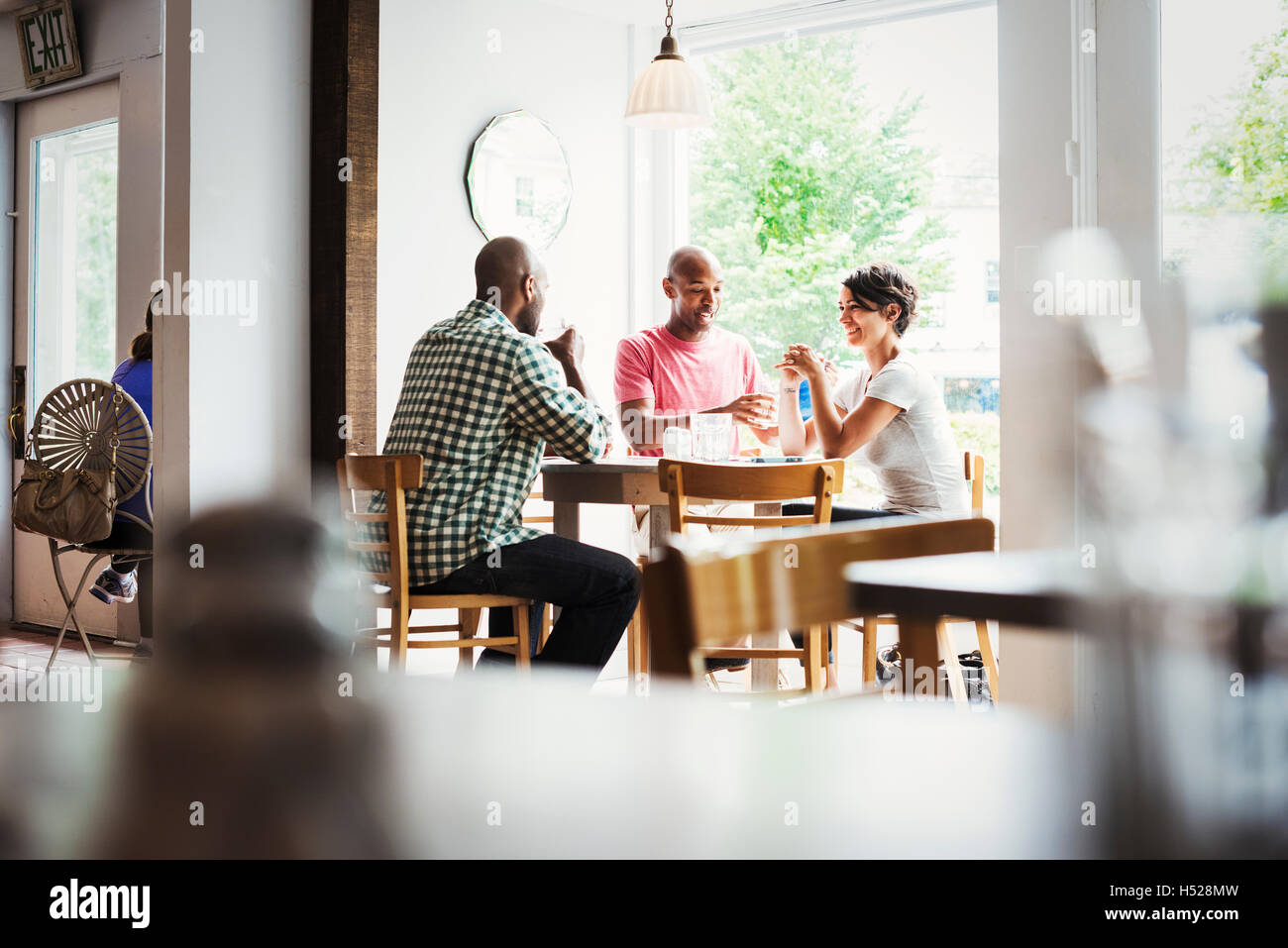 Zwei Männer und eine Frau sitzen an einem Tisch in einem Café zu Mittag. Stockfoto