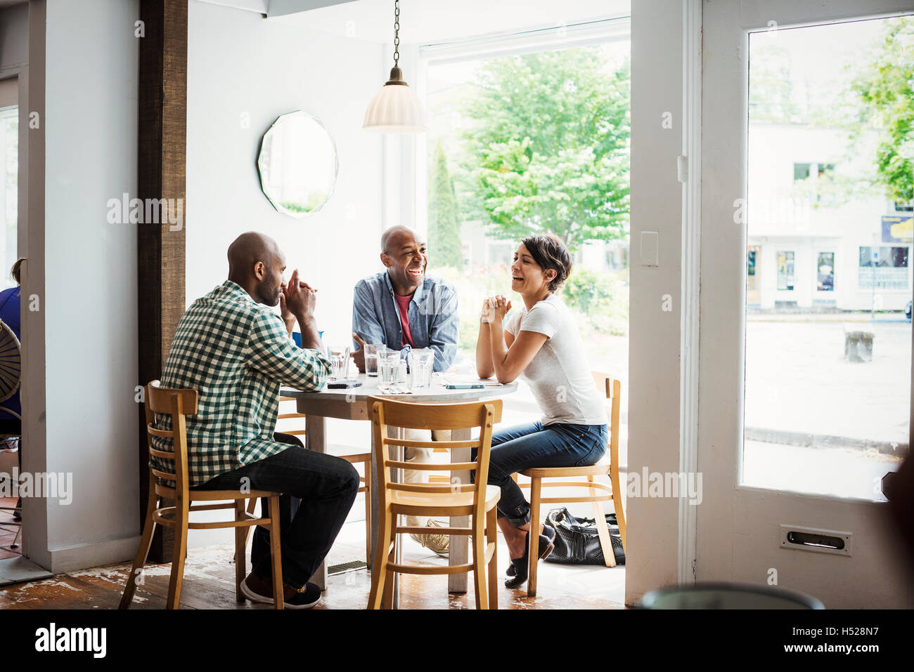 Zwei Männer und eine Frau sitzen an einem Tisch in einem Café zu Mittag. Stockfoto