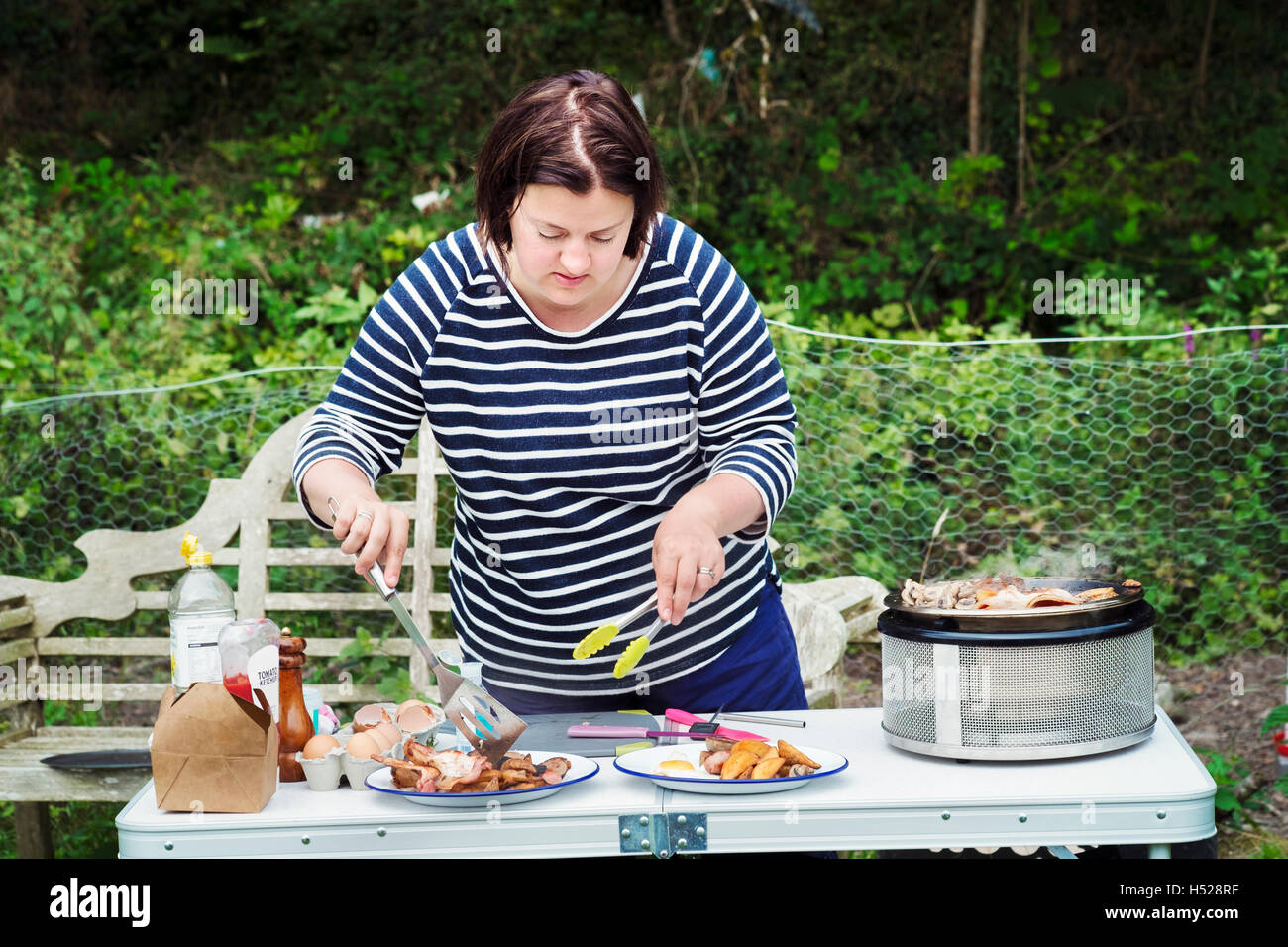 Frau an einem camping-Tisch, zwei Platten von Lebensmitteln vorbereitet. Stockfoto