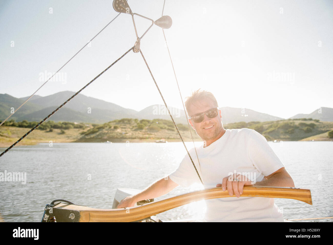 Porträt von einem blonden Mann mit Sonnenbrille, die Lenkung eines Segelbootes. Stockfoto