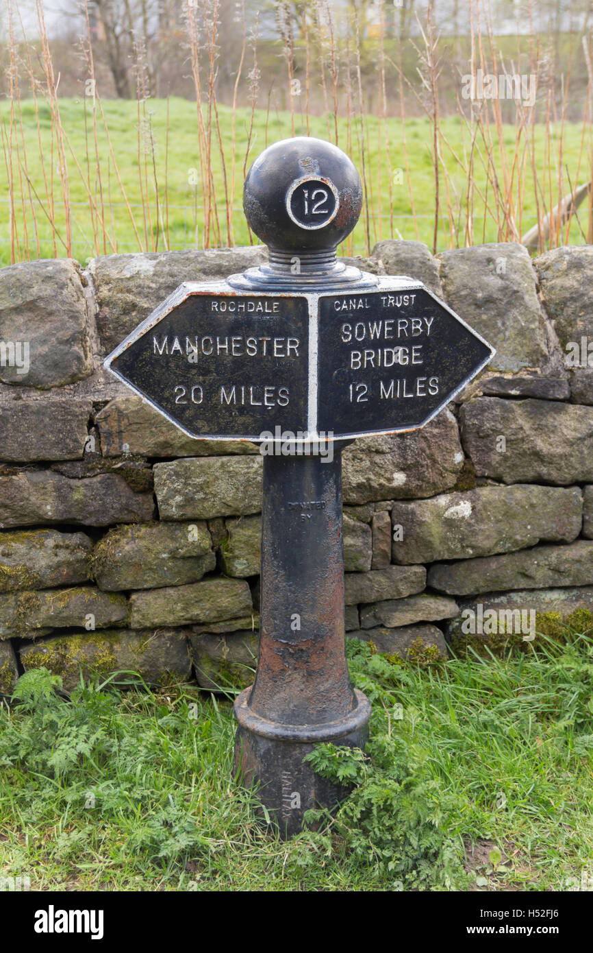 Gusseisen-Meilenstein 12 am Rochdale Kanal in dem Dorf Walsden in der Nähe von Todmorden an der Grenze von Lancashire/Yorkshire. Stockfoto