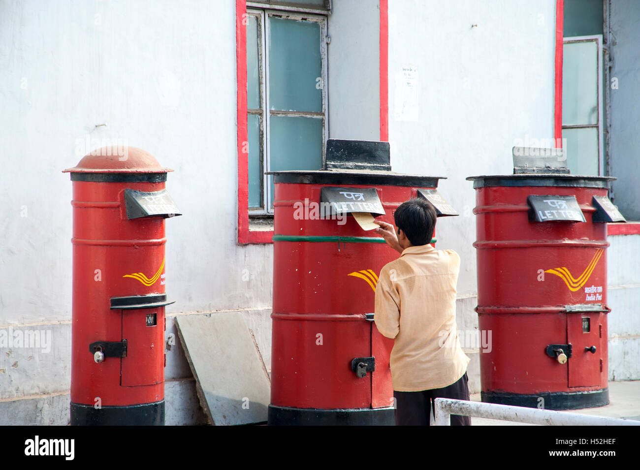 Mann Entsendung Buchstaben in der Mitte der drei Briefkästen außerhalb der General Post Office in Old Delhi Stockfoto