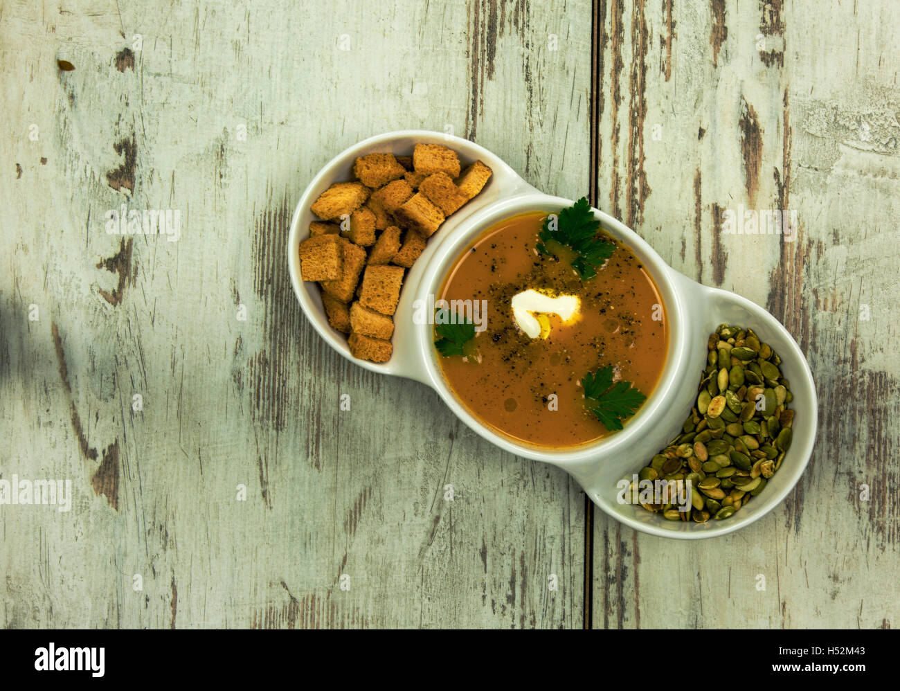 Weiße Schale mit Kürbissuppe, Kürbiskerne und kleinen, gebackenen Croutons Brot, die frischen Blätter von Petersilie und Sahne zubereitet ein Stockfoto