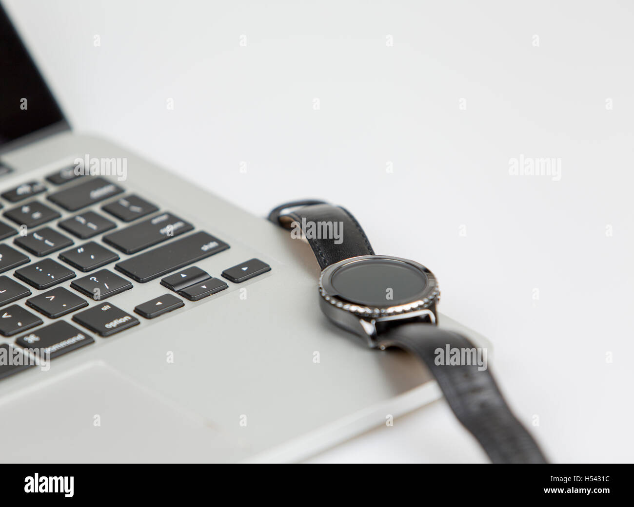 Smartwatch auf einem Laptop. Smartwatch im Standby-Modus, Fokus auf Tastatur. Studio gedreht auf weißem Hintergrund Stockfoto