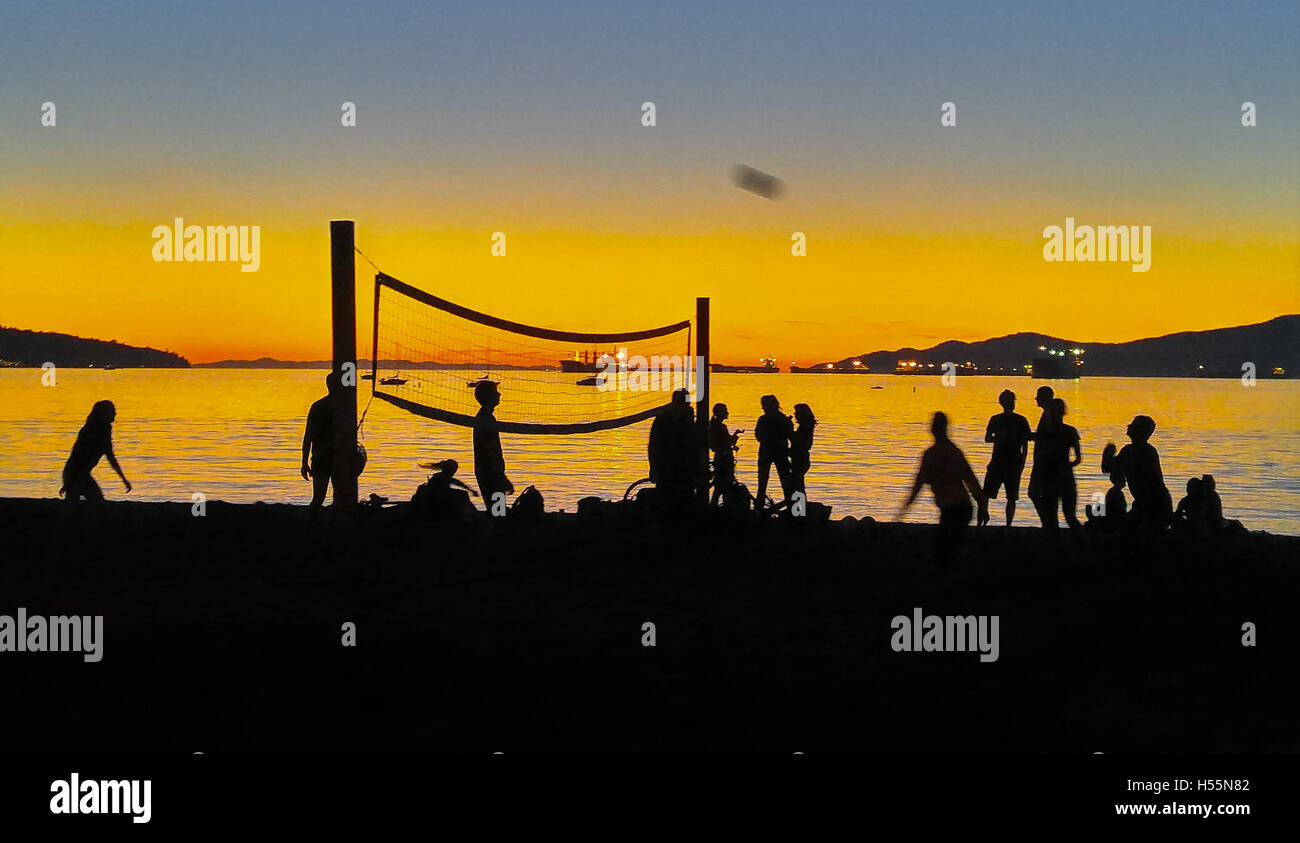 Volley-Ball-Teams spielen in der Silhouette gegen Sonnenuntergang am Strand. Stockfoto