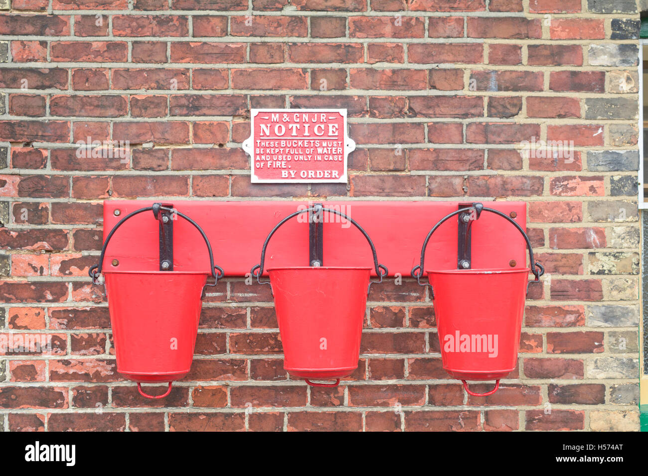 Drei rote Feuer Eimer auf Plattform am Bahnhof Sheringham, Teil der North Norfolk Railway, England Stockfoto