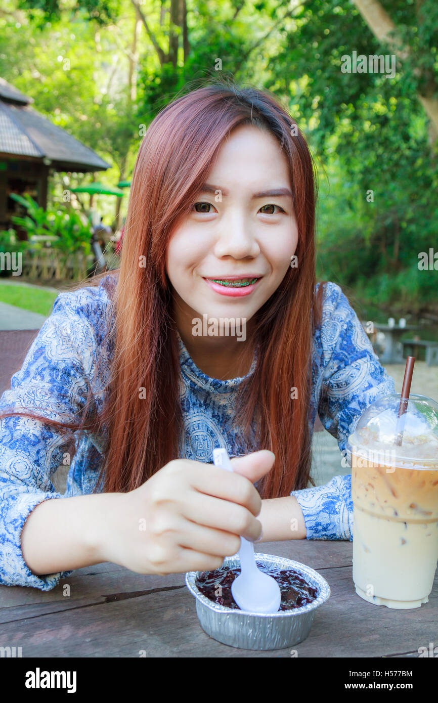Asiatische Teenager Essen Blaubeeren Käsekuchen und Eis Kaffee im Resort. Stockfoto