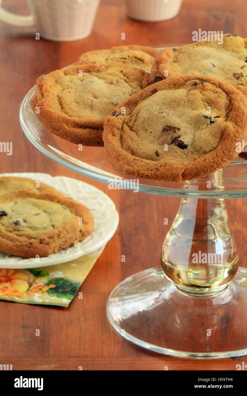 Frisch gebackene Schokoladenkekse auf Glas Etagere mit zwei Cookies auf einem Teller. Querformat.  Natürliches Licht Stockfoto