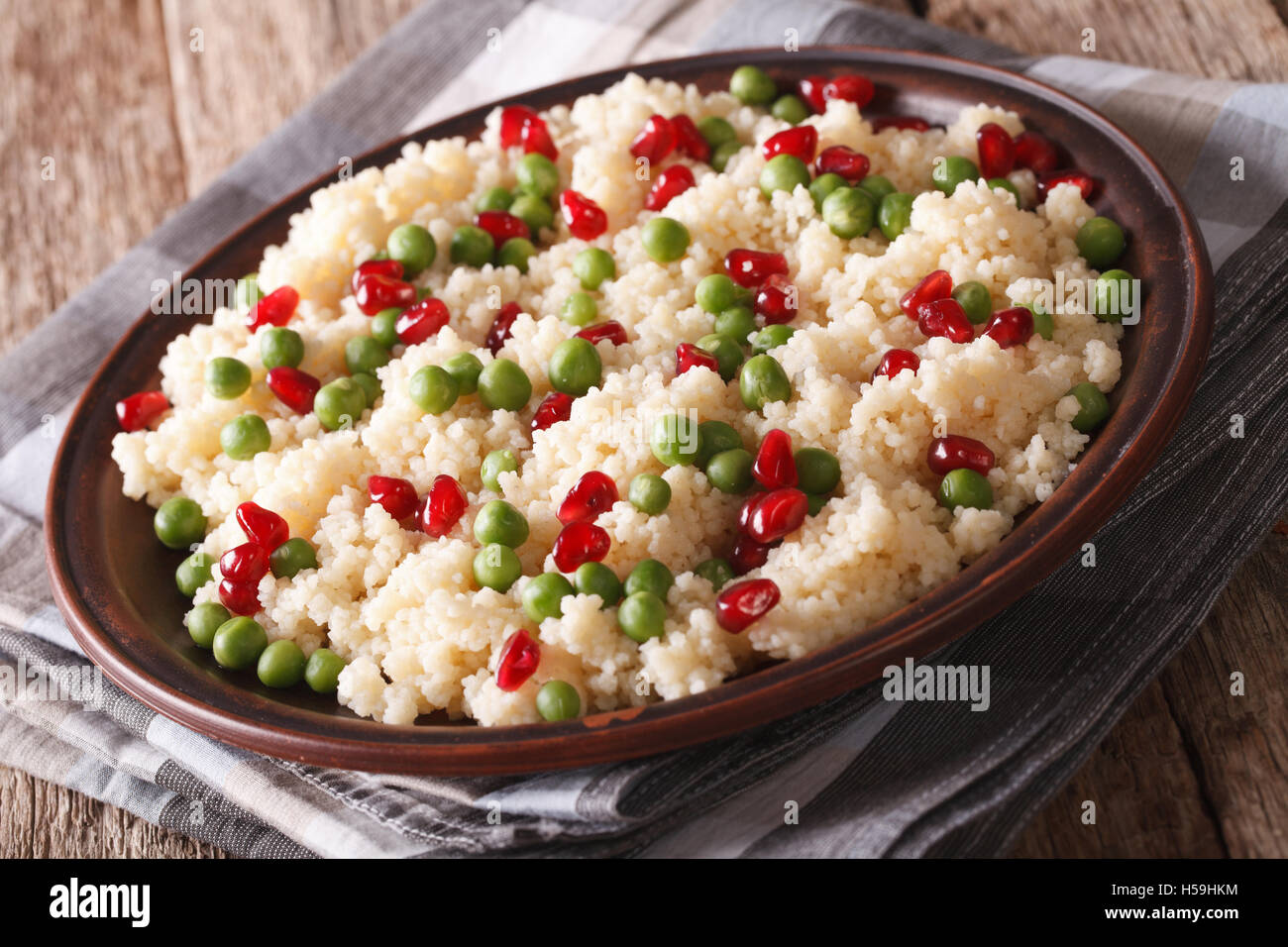 Couscous-Salat mit grünen Erbsen und Granatapfel-close-up auf dem Tisch ...