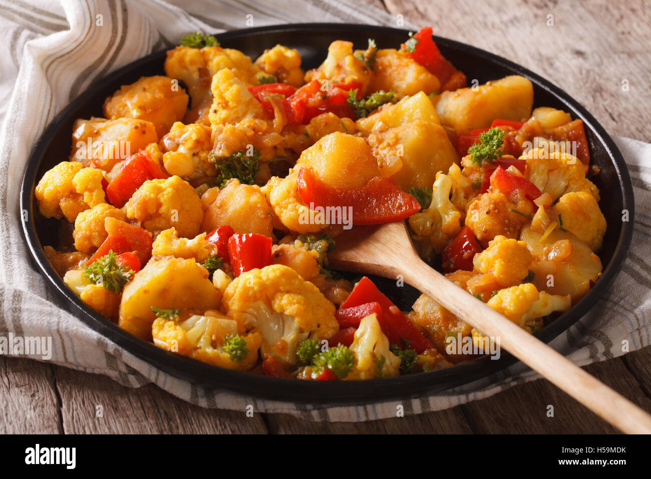 Aloo Gobi Blumenkohl und Kartoffeln hautnah auf einem Teller auf den Tisch. horizontale Stockfoto