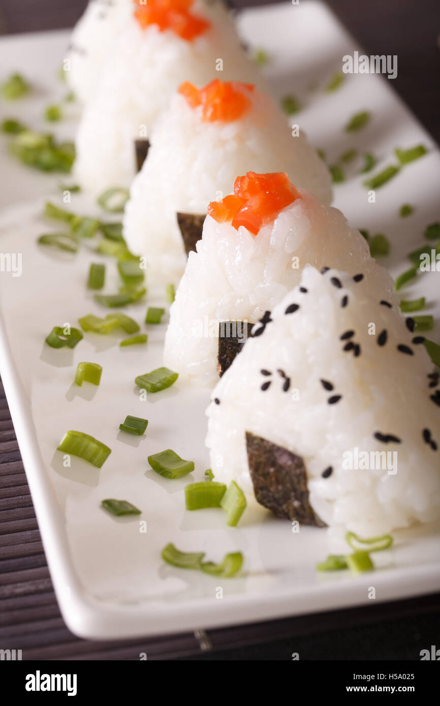 Japanisches Essen Onigiri Reis Kugeln close-up auf einem weißen Teller. vertikale Stockfoto Japanisches Essen Onigiri Reis Kugeln close-up auf einem weißen Teller. vertikale Stockfoto